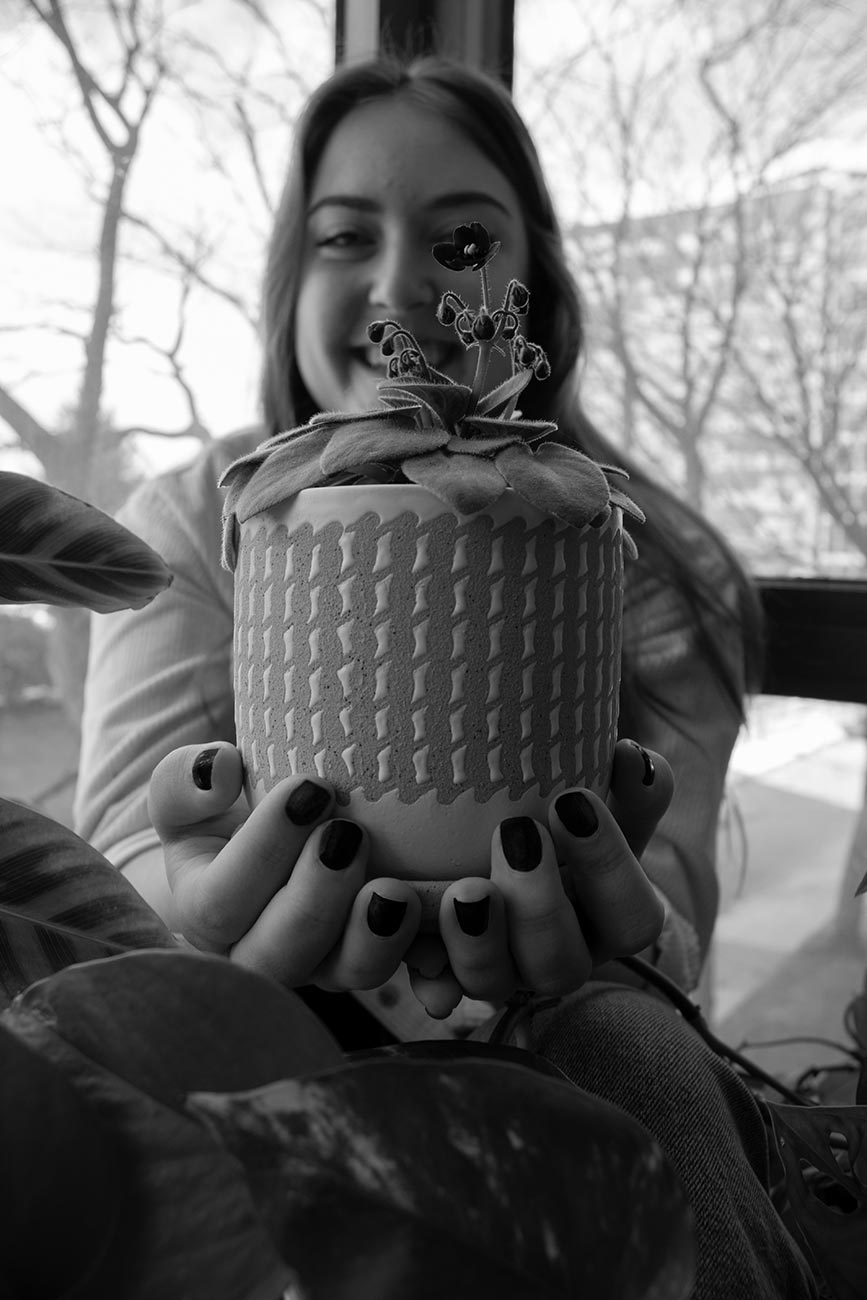 Black and white, Girl holding up a flower pot so the flower covers her left eye